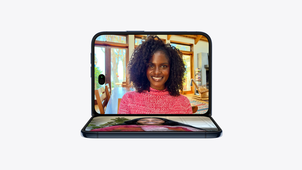 A black foldable smartphone shown open against a light gray background, with a video call or portrait displayed on the screen.