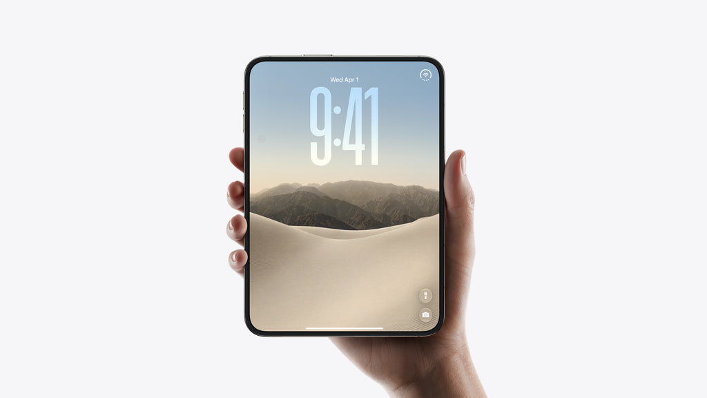 A hand holding a smartphone with a large screen displaying a mountain and dune wallpaper, set against a clean white background.